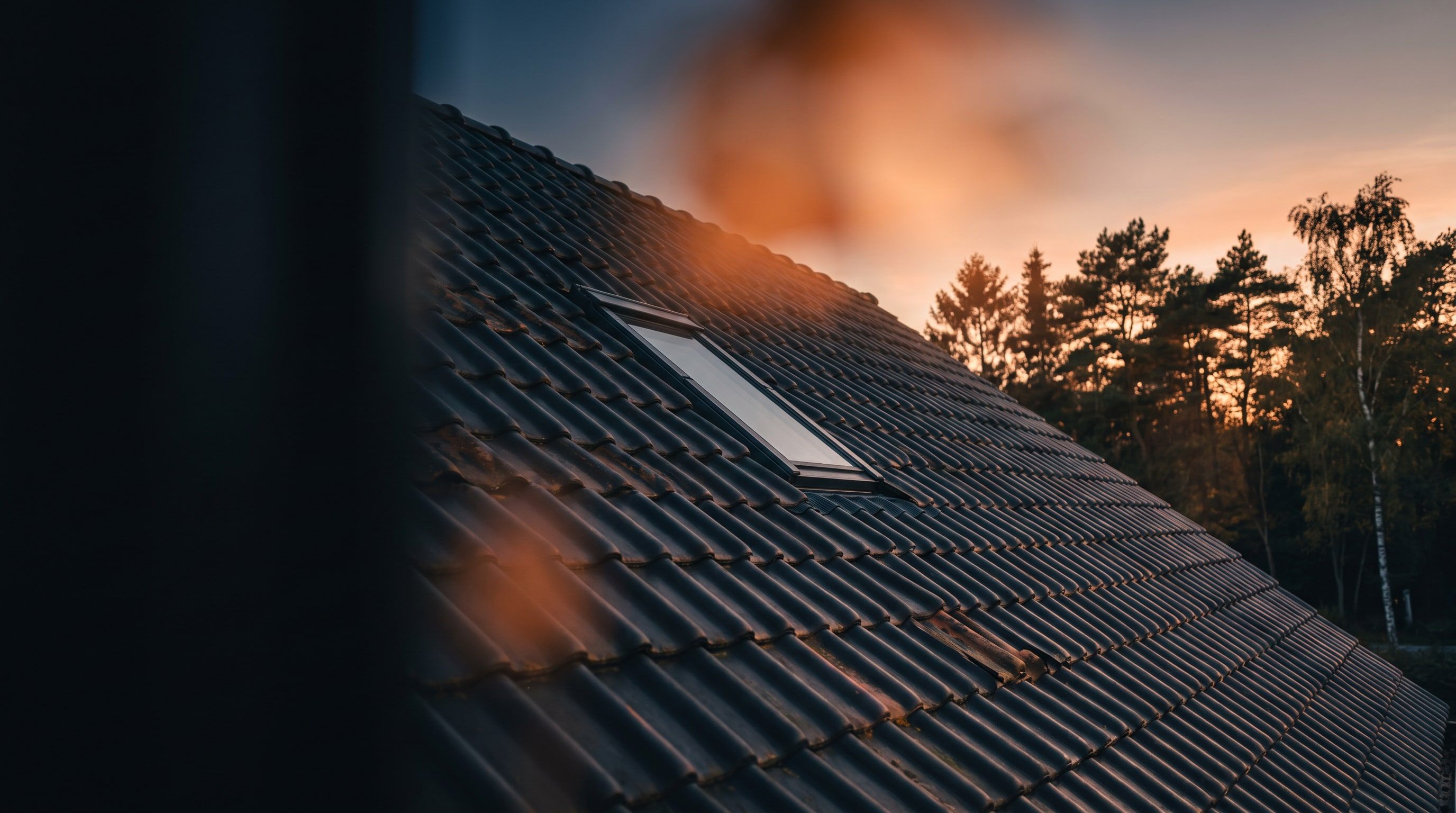 Donker Nederlands pannendak met dakraam bij zonsondergang